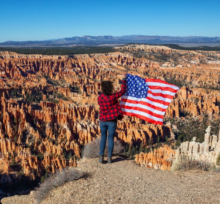 Woman standing with american flag in Bryce Canyon. 